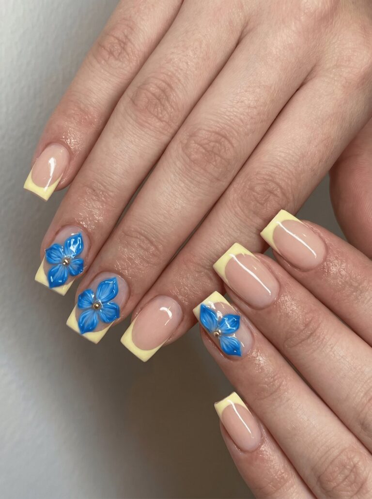 Soft yellow French manicure with blue 3D flowers at a nail salon in Victoria BC